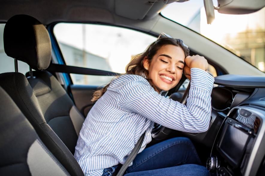 hispanic woman hugging car stirring wheel